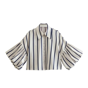 Dettaglio camicia a righe beige con maniche a sbuffo e bottoni sul davanti
