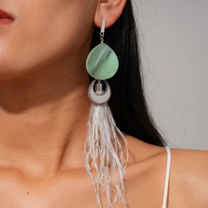 Close-up of model wearing boho resin earrings with mint green petals and long feathers