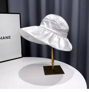 Detail of white satin sun hat featuring sparkling rhinestones on a gold display stand