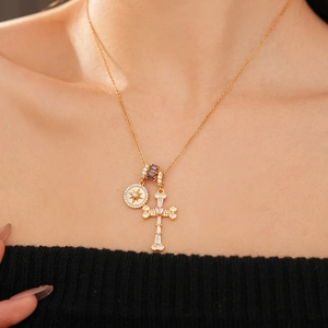 Detailed close-up of 18k gold-plated necklace featuring zircon cross and star coin pendant