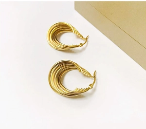 Detailed view of twisted 18K gold water-wave earrings on a premium gift box background