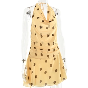 Detailed close-up of yellow polka dot halter mini dress with ruffled hem and pleated design