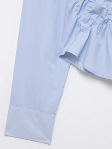 Détail de chemise en popeline bleu clair avec plis élastiques et coutures précises