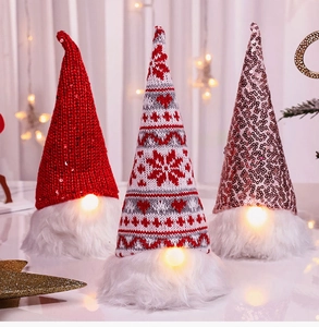 Close-up of three glowing Christmas gnomes with sequins and warm LED lights