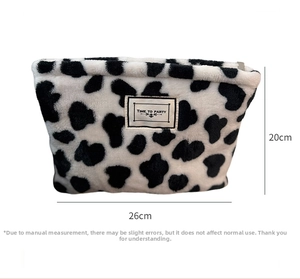 Detail of plush cow print makeup bag with label showing 26cm width and 20cm height dimensions