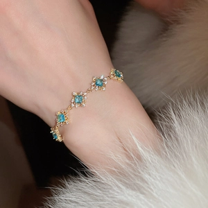 Close-up of gold bracelet featuring geometric square blue zircon and pavé crystals
