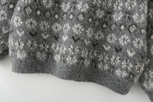 Detailed macro view of the grey and white jacquard knit sweater showing plush fabric texture
