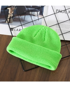 Detailed knit texture of a neon green winter beanie on a rustic wooden surface