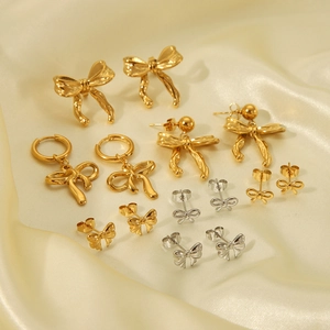 Elegant bow knot earrings set in gold and silver finish on silk fabric background