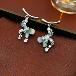 Macro view of silver bow drop earrings with light green petals and sparkling zircon stones