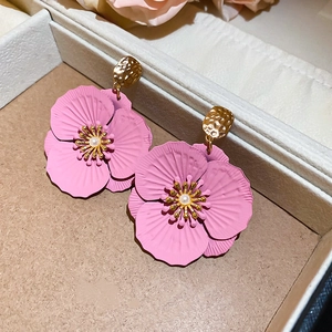 Détail de boucles d'oreilles fleur rose avec perle dans une boîte à bijoux