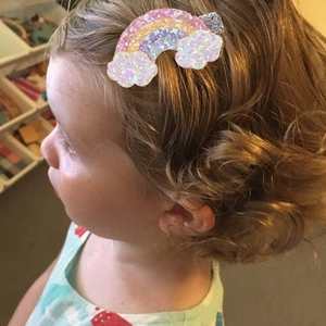 Glitter rainbow and cloud hair clip worn on a child for hair styling effect