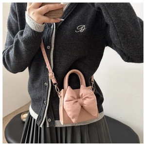 Pink PU leather crossbody bag with oversized bow detail shown in a mirror selfie