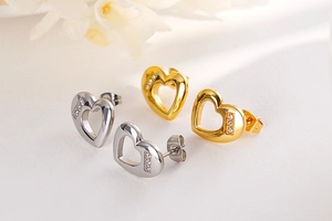 Detail of silver and gold heart stud earrings with sparkling pavé crystal accents
