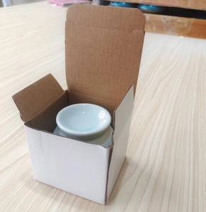 Mini ceramic cigar holder in a white protective gift box on a light wooden table