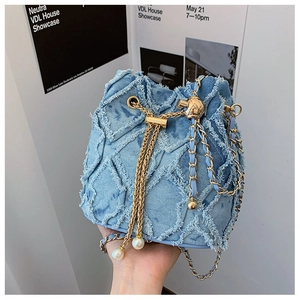 Detail of blue denim bucket bag with frayed quilted patterns and pearl drawstring