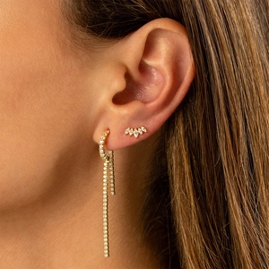 Detailed close-up of gold chain fringe earrings with marquise cubic zirconia on ear