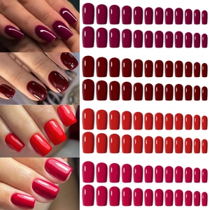 Short square press-on nails in deep red and magenta shades with a glossy finish