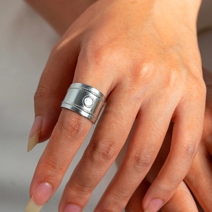 Macro shot of silver wide-band snake-style ring with embossed relief on model finger