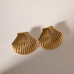 Detailed close-up of 18K gold-plated stainless steel shell earrings on textured surface