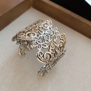 Close-up of vintage floral hollow metal cuff bracelet with detailed filigree patterns