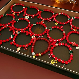 Détails macro des perles de cinabre rouge avec pendentifs dragon doré et Fu sur bracelets