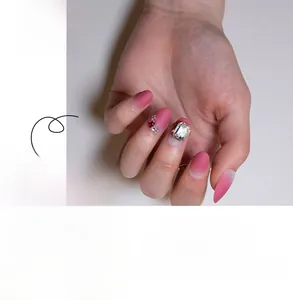 Detail of short round press-on nails with pink gradient and luxury rhinestone accents