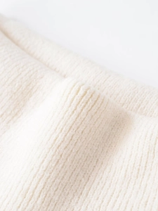Macro close-up of cream white rib knit fabric showing fine texture and soft fiber details