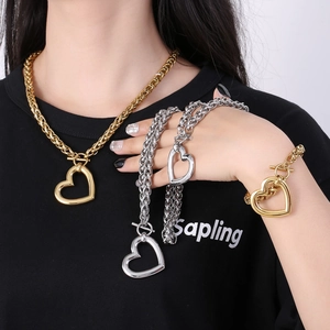 Close-up of chunky gold and silver chain jewelry set with heart pendants and OT clasps