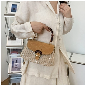 Detail of hand-woven straw bag featuring floral embroidery and a natural bamboo handle