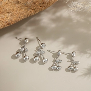 Close-up of silver cherry earrings with sparkling crystals and leaf details