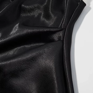 Gros plan sur la texture du tissu satiné noir avec des drapés élégants et un fini soyeux