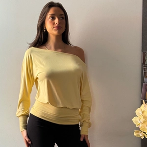 Detail of light yellow off-the-shoulder knit top featuring a slim fit and long sleeves
