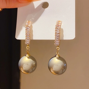 Détail de boucles d'oreilles nœud en argent S925 plaqué or avec grandes perles grises