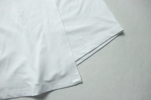 Gros plan sur un tissu tricoté blanc avec ourlet à double surpiqûre et texture fine