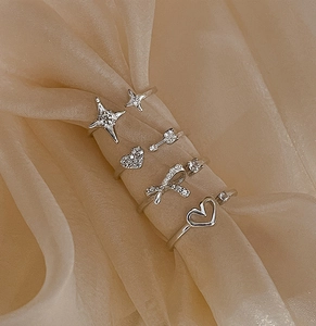 Close-up of sparkling bow and star ring set with silver heart charms and zircons