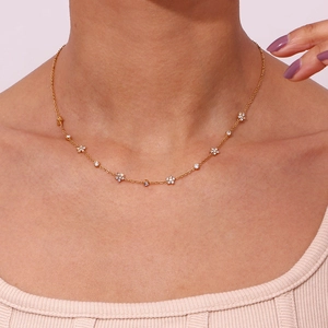 Minimalist gold link necklace with floral zircon pendants worn on a woman neck