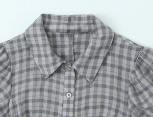 Detailed view of grey plaid dress featuring lapel collar, stitching and round buttons