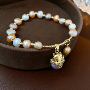 Gros plan d'un bracelet en perles multicolores et perles dorées avec pendentif chat de la fortune