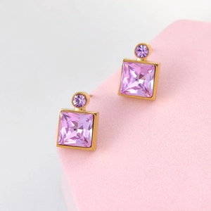 Elegant gold square pink crystal earrings on a matte pink pedestal with a grey background