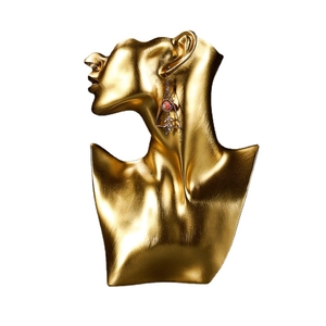 Golden resin bust jewelry display stand showing an earring with red stone and metal leaf