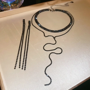 Detail von luxuriösem Strass-Choker und langen Fransenohrringen in Gunmetal-Optik
