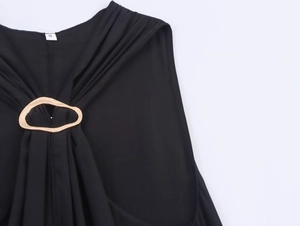 Detail eines schwarzen Halterneck-Tops mit dekorativer goldener Metallschnalle und S-Tag