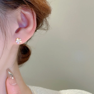 Élégantes boucles d'oreilles fleur dorées avec zircone portées par un mannequin