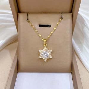 Detailed view of a gold snowflake necklace with zircon inlay on a brown jewelry box