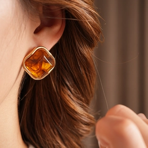 Detail of vintage geometric gold square earring with amber resin gemstone on a model