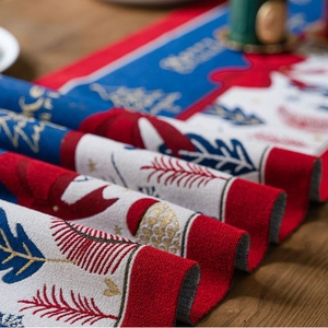 Jacquard Christmas table runner with festive tree patterns on a rustic wooden dining table