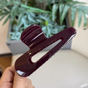 Dettaglio di un grande fermaglio per capelli a goccia viola scuro lucido e traforato