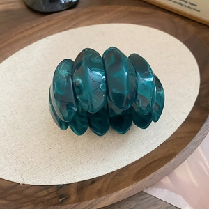 Close-up of teal marbled acrylic elastic bracelet with smooth oval resin links