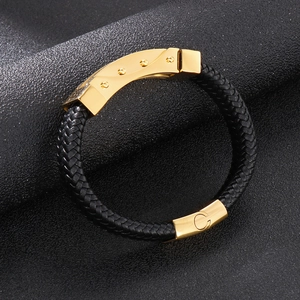 Close-up of black braided leather men's bracelet with polished gold metal clasp